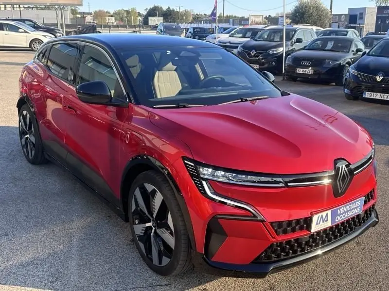 Renault Mégane E-Tech Electric rouge flamme en 3/4 avant droit, avec calandre distinctive et jantes modernes.