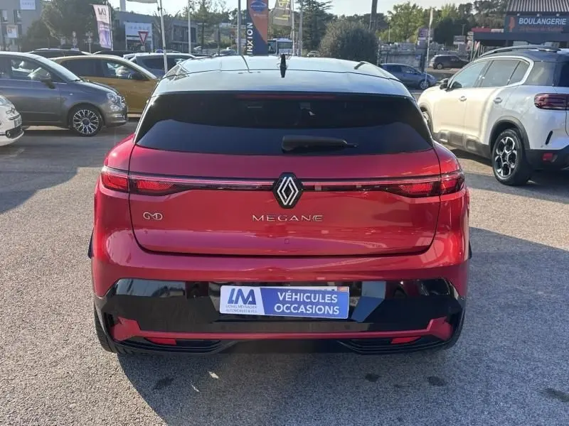 Vue arrière d'une Renault Mégane E-Tech Electric rouge flamme 2023, avec logo central et feux LED continus.