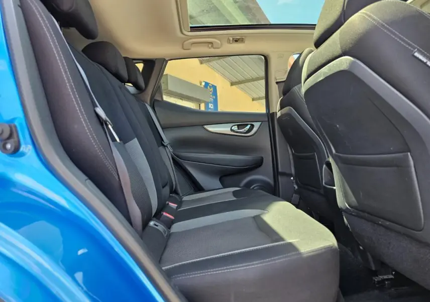 Vue intérieure arrière côté gauche du Nissan Qashqai bleu 2019, montrant les sièges arrière et le toit ouvrant panoramique.