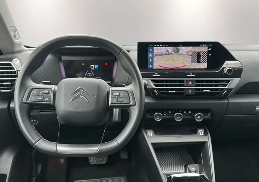 Vue intérieure frontale du tableau de bord et volant cuir noir de la Citroën C4 avec écran tactile affichant la caméra de recul.