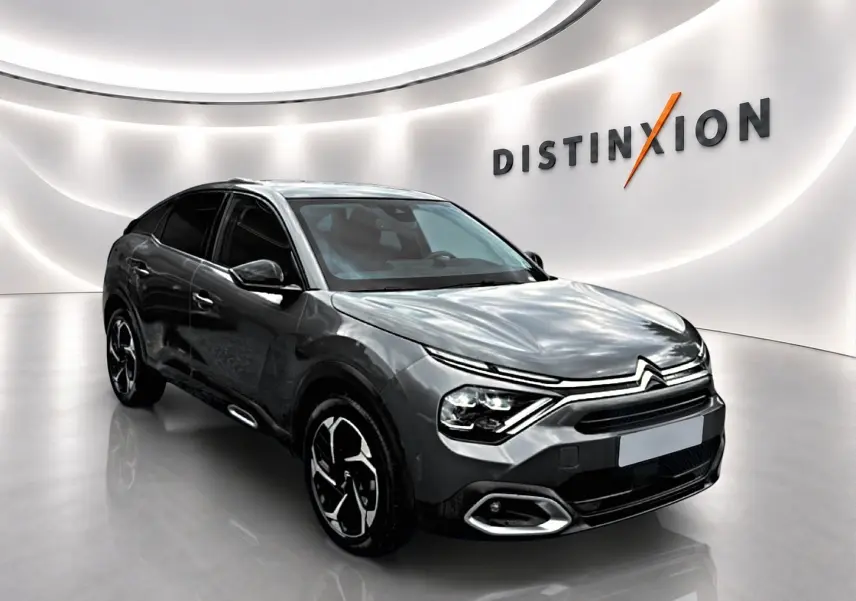 Citroën C4 gris 3/4 avant droit dans showroom avec jantes alu et vitres teintées.