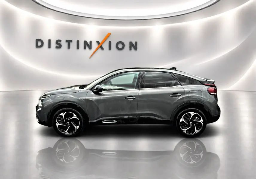 Profil droit d'une Citroën C4 gris métallisé 2024 avec jantes alliage, dans un showroom lumineux au logo Distinxion.