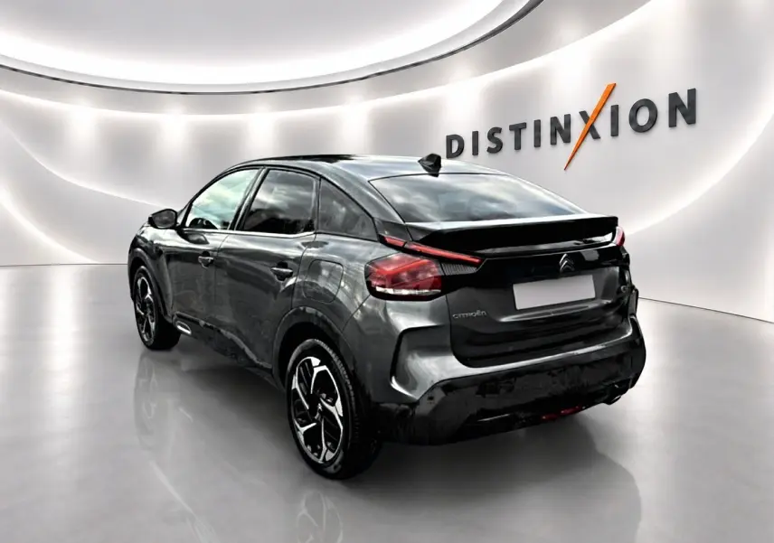Vue 3/4 arrière droite d'une Citroën C4 gris métallisé avec jantes alliage dans un showroom lumineux.