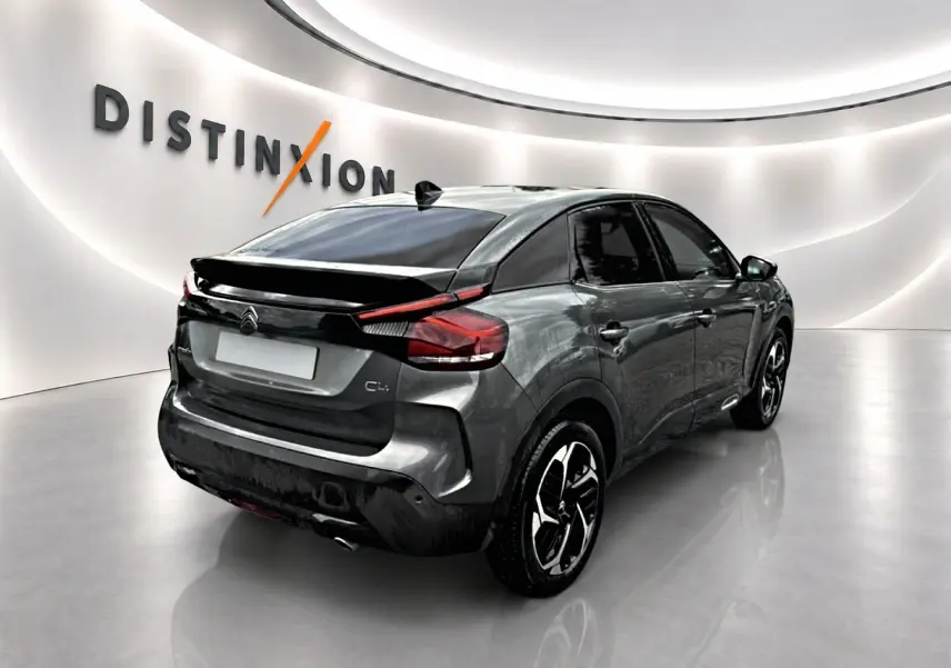 Vue 3/4 arrière droite d'une Citroën C4 gris métallisé avec jantes alliage et vitres surteintées en showroom.