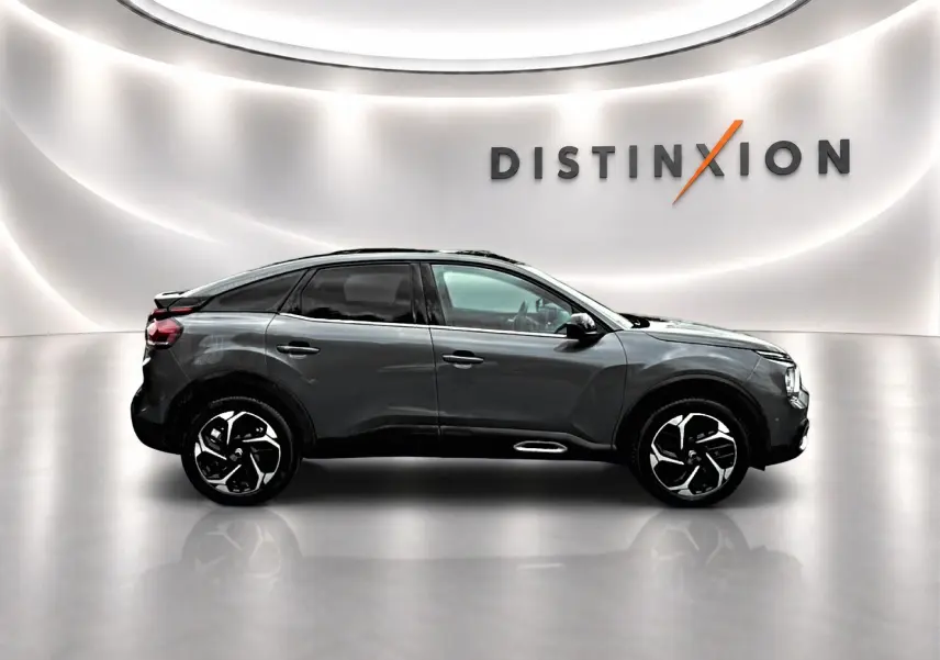 Profil droit d'une Citroën C4 gris métallisé 2024 avec jantes alliage et vitres teintées, sur fond lumineux blanc.
