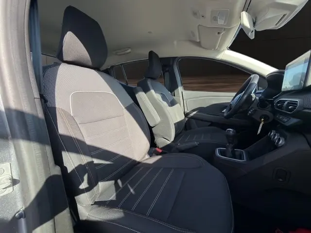 Vue intérieure côté gauche avant de la Dacia Sandero Stepway 2025, sièges tissu gris et tableau de bord avec écran tactile.