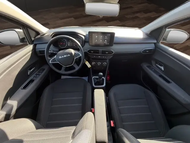 Vue intérieure avant de la Dacia Sandero Stepway 2025 gris foncé, avec tableau de bord moderne et écran tactile central.