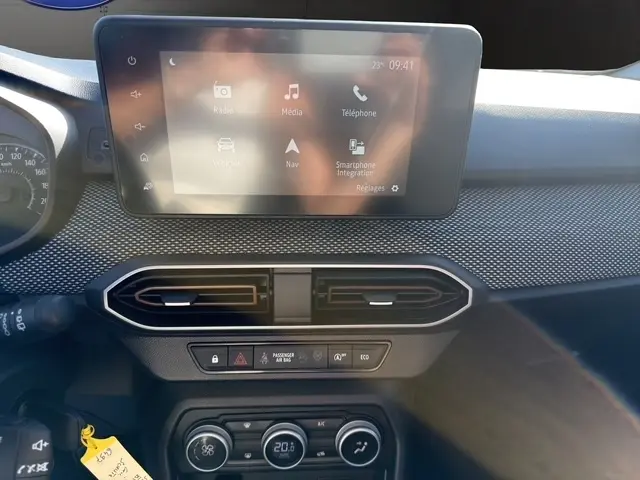 Vue rapprochée du tableau de bord central gris foncé de la Dacia Sandero Stepway 2025 avec écran tactile et commandes climatisation digitales.