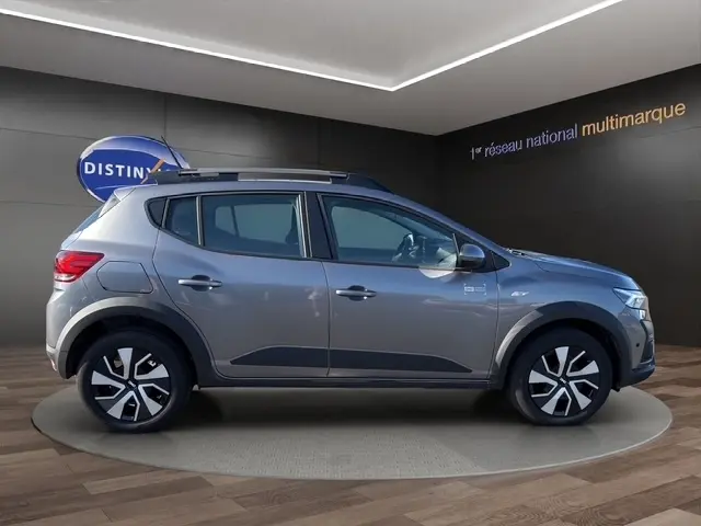 Vue de profil côté gauche d'une Dacia Sandero Stepway gris foncé avec rails de toit et jantes alliage distinctives.