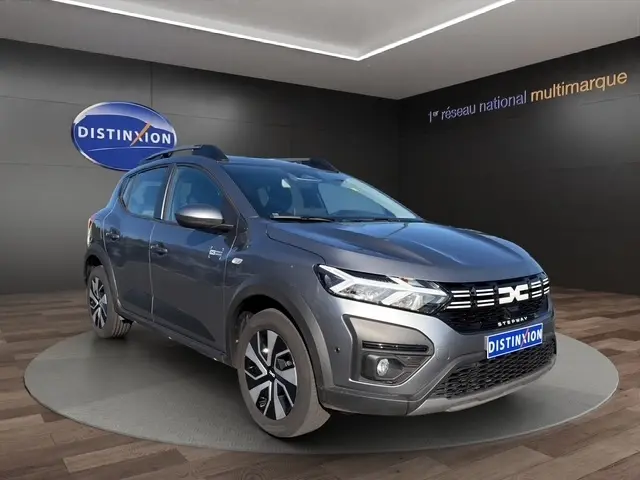 Vue 3/4 avant droite d'une Dacia Sandero Stepway gris foncé avec calandre distinctive et jantes alliage bicolores.