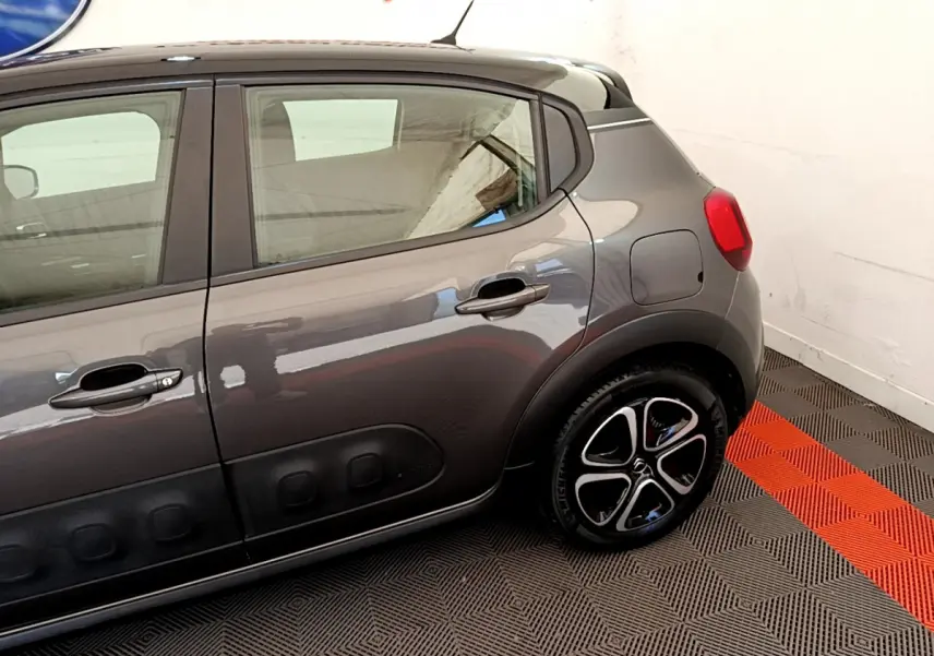 Vue latérale droite d'une Citroën C3 gris foncé avec protections de porte noires et jantes distinctives.