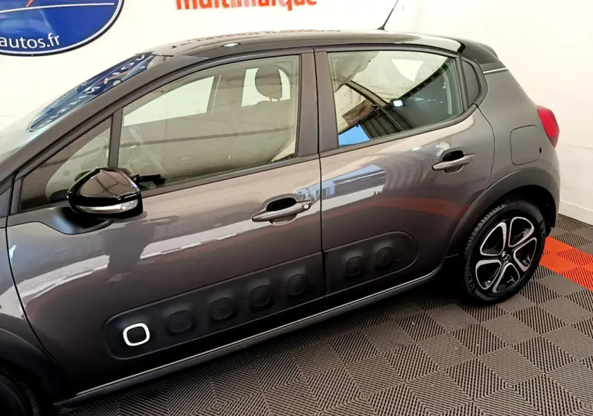 Profil côté gauche d'une Citroën C3 gris foncé avec protections latérales noires et jantes distinctives.