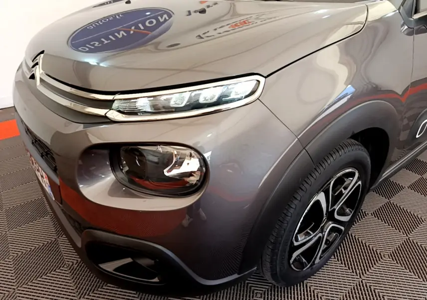 Vue 3/4 avant droit d'une Citroën C3 gris foncé avec phares LED et jantes alliage distinctives.