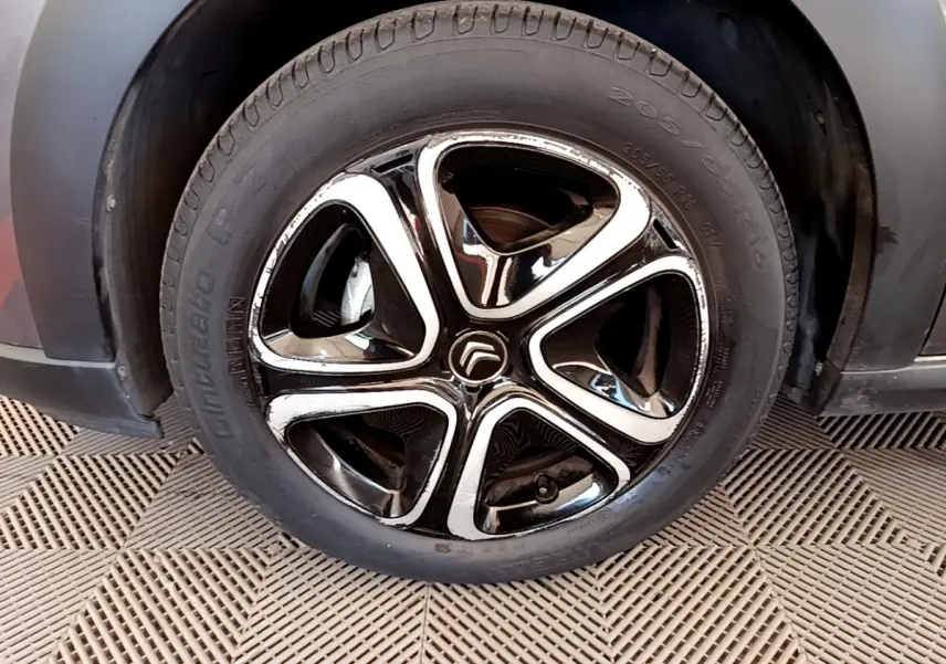 Gros plan sur la jante noire et chromée d'une Citroën C3 gris foncé, roue avant droite visible.