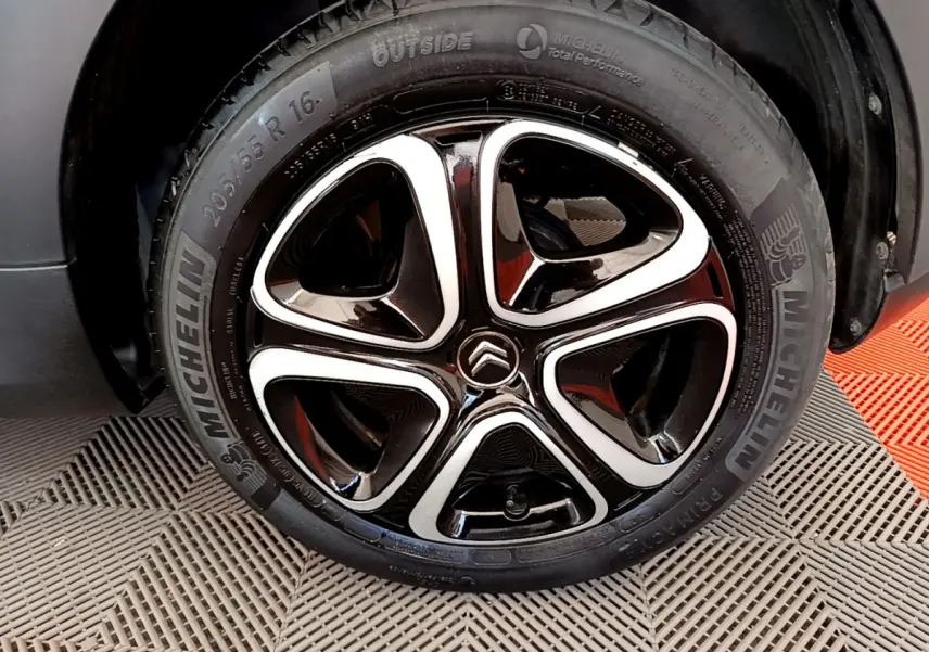 Gros plan sur la roue avant droite d'une Citroën C3 gris foncé, jante alliage noire et argentée avec logo Citroën central.