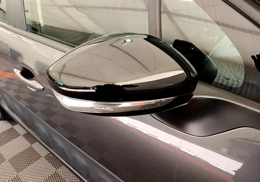 Rétroviseur droit noir brillant avec clignotant intégré sur Citroën C3 gris foncé vue de profil rapprochée.