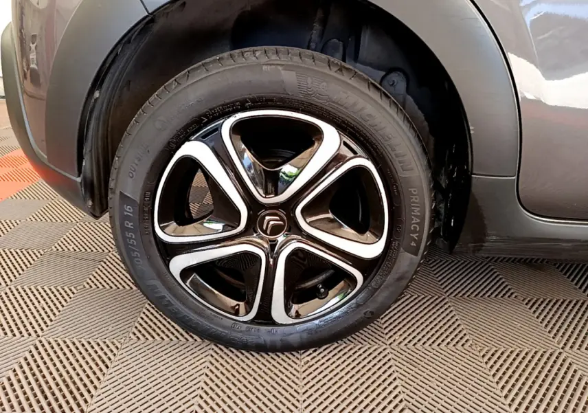 Gros plan sur la roue avant gauche de la Citroën C3 gris foncé, soulignant la jante noire et chromée au design moderne.