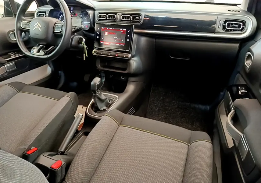 Vue intérieure avant de la Citroën C3 PureTech 82 Shine 2019, tableau de bord noir avec écran tactile central et volant cuir.