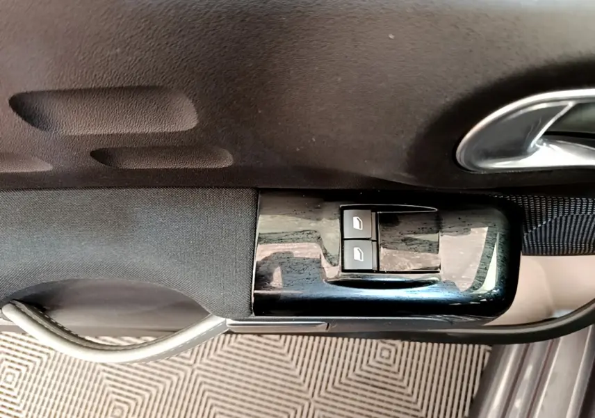 Gros plan sur les commandes des vitres électriques côté conducteur d'une Citroën C3 gris foncé 2019.