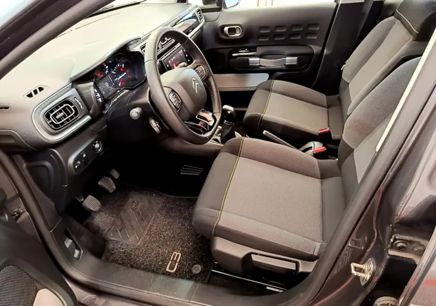 Intérieur avant droit de la Citroën C3 gris foncé 2019, avec tableau de bord tactile et sièges tissu gris.