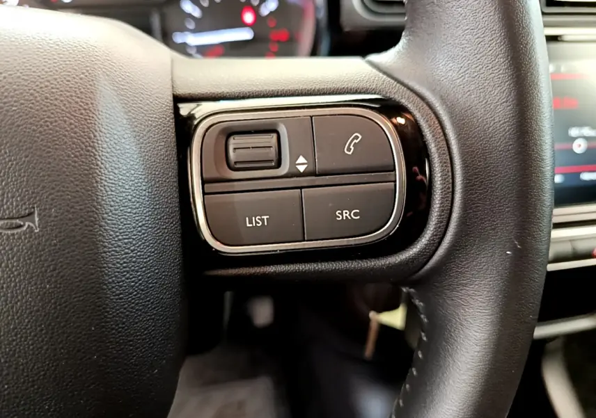 Gros plan sur les commandes gauche du volant cuir noir de la Citroën C3 Shine 2019, avec boutons multifonctions.