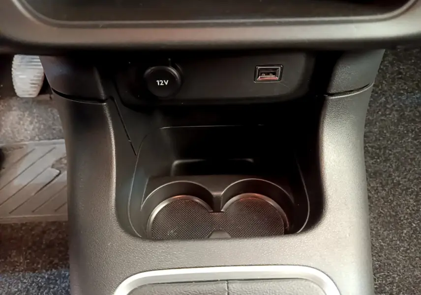 Gros plan sur la console centrale noire de la Citroën C3 2019 avec prise 12V, port USB et porte-gobelets.