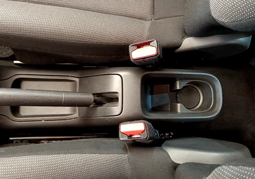 Vue rapprochée de la console centrale avec frein à main et porte-gobelet entre les sièges avant gris foncé d'une Citroën C3.