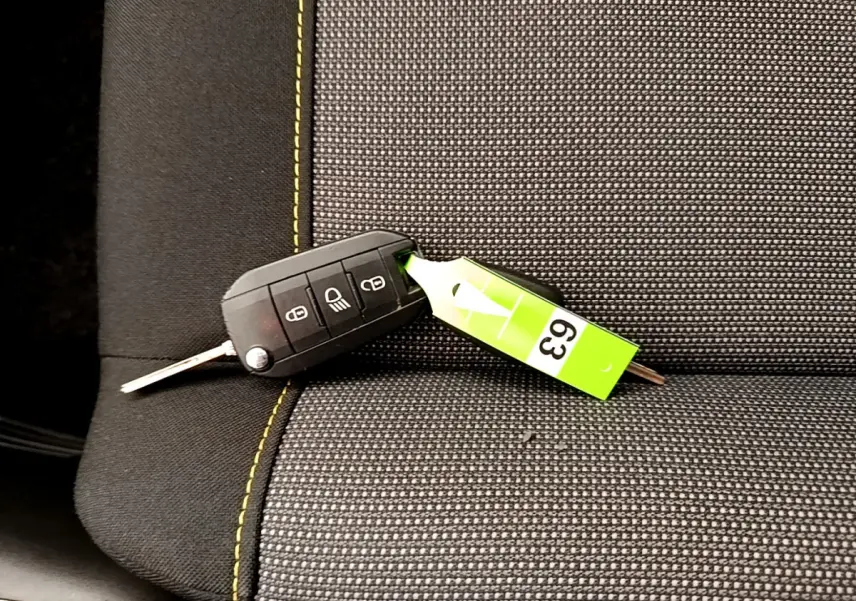 Clé de voiture noire posée sur un siège tissu gris foncé avec surpiqûres jaunes dans une Citroën C3.