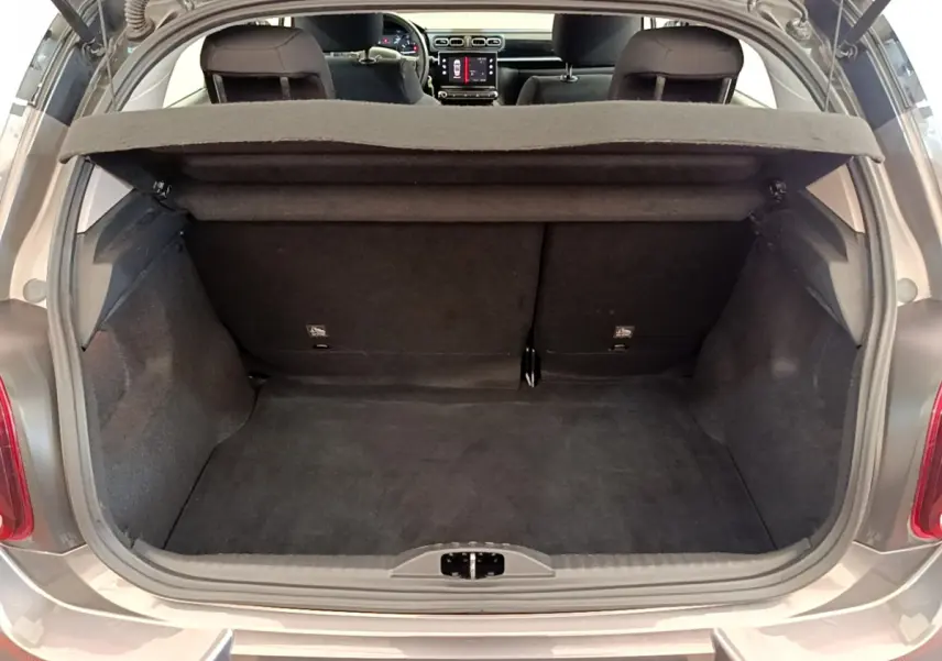 Coffre ouvert d'une Citroën C3 gris foncé vue arrière, banquette arrière et tableau de bord visibles à l'intérieur.