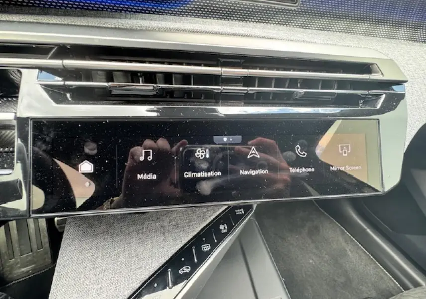 Vue rapprochée de l’écran tactile central noir brillant du Peugeot 3008 gris Artense avec commandes multimédia et climatisation.