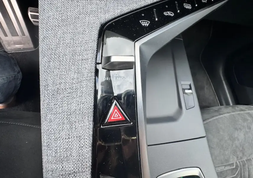 Détail de la console centrale noire brillante avec bouton de mode de conduite et alerte de danger dans un Peugeot 3008 gris Artense 2024.
