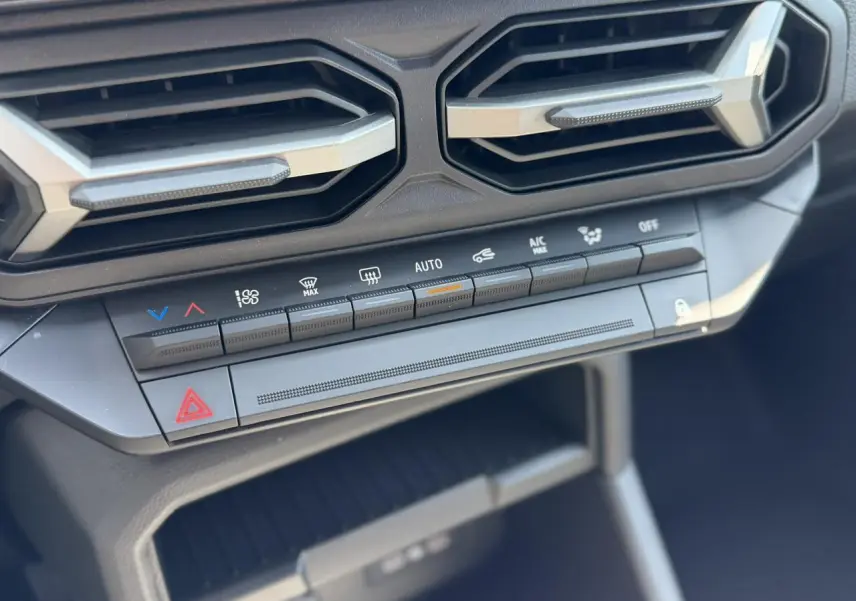 Détail des commandes de climatisation et des aérateurs hexagonaux du tableau de bord du Dacia Duster 2026.