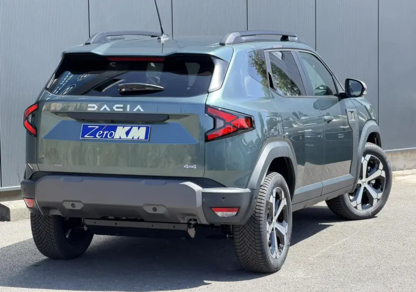 Vue 3/4 arrière droite du Dacia Duster 2026 Vert Cèdre avec barres de toit et jantes alliage 18 pouces.