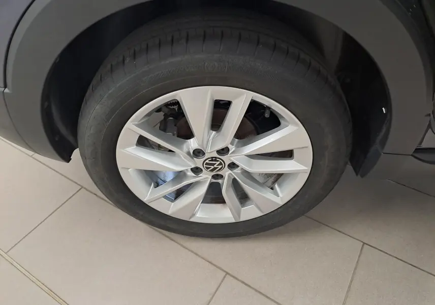 Gros plan sur la roue avant droite du Volkswagen T-Cross gris cendré avec jante alliage à 5 doubles branches.
