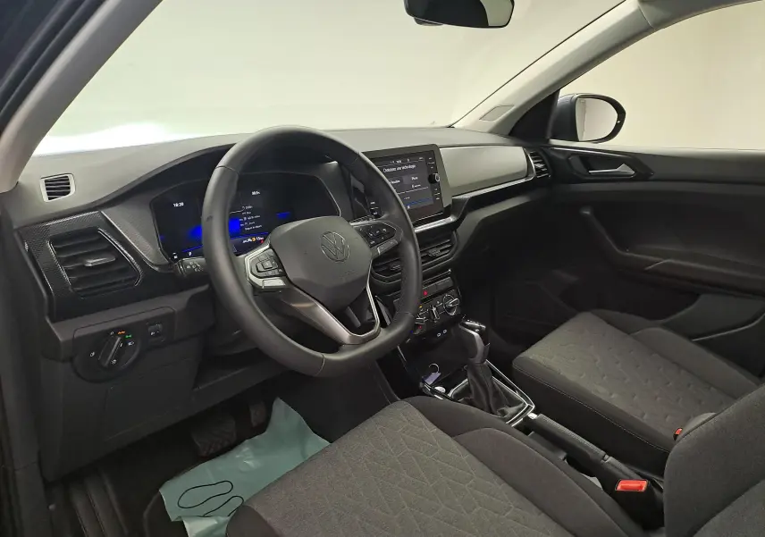 Vue intérieure côté conducteur du Volkswagen T-Cross 2025, tableau de bord moderne avec écran tactile et volant multifonction noir.