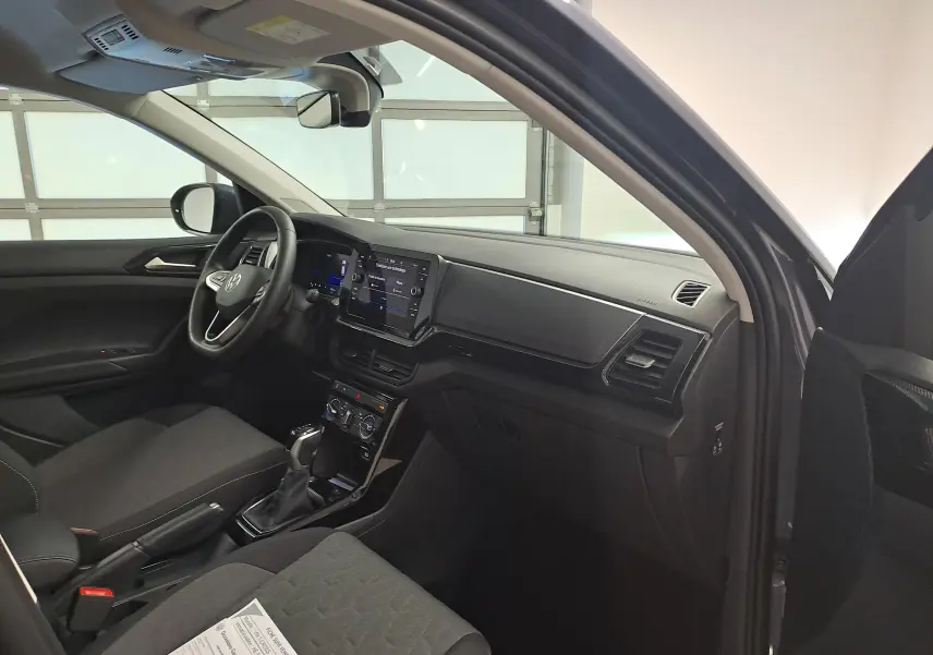 Vue intérieure côté conducteur du Volkswagen T-Cross gris cendré, mettant en valeur le tableau de bord et l'écran tactile central.