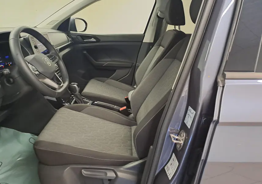 Vue intérieure côté gauche du Volkswagen T-Cross gris cendré, montrant les sièges avant et le tableau de bord moderne.
