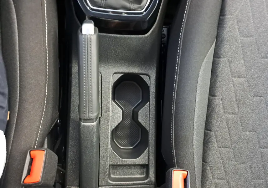 Vue plongeante sur la console centrale du Volkswagen T-Cross 2025, avec frein à main et porte-gobelets noirs.