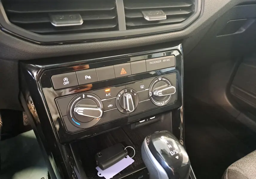 Vue rapprochée de la console centrale du Volkswagen T-Cross 2025 gris cendré, avec commandes climatisation et levier de boîte auto.