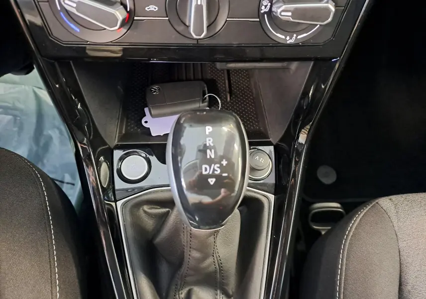 Vue rapprochée du levier de vitesses automatique noir du Volkswagen T-Cross gris cendré avec bouton start/stop et prise 12V.