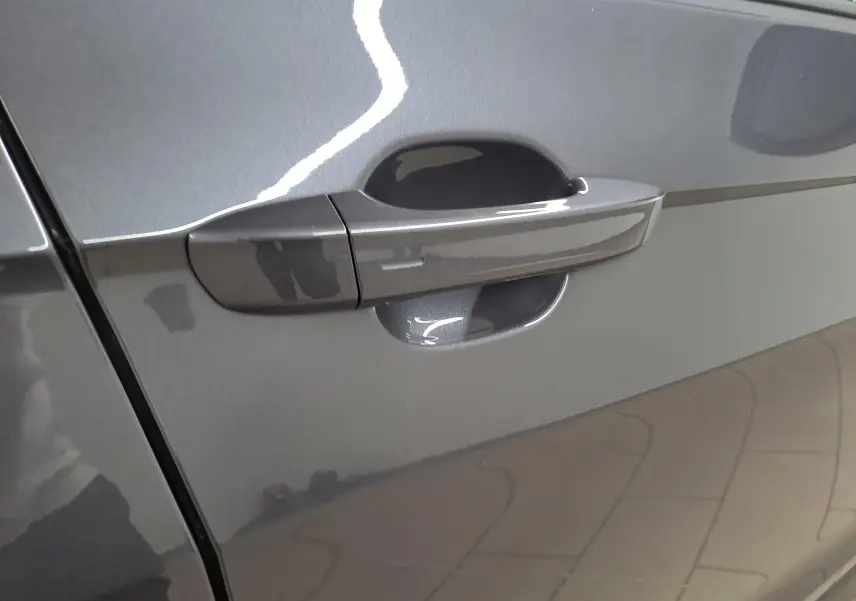 Poignée de porte côté gauche du Volkswagen T-Cross 2025 en gris cendré métallisé avec reflet intérieur.
