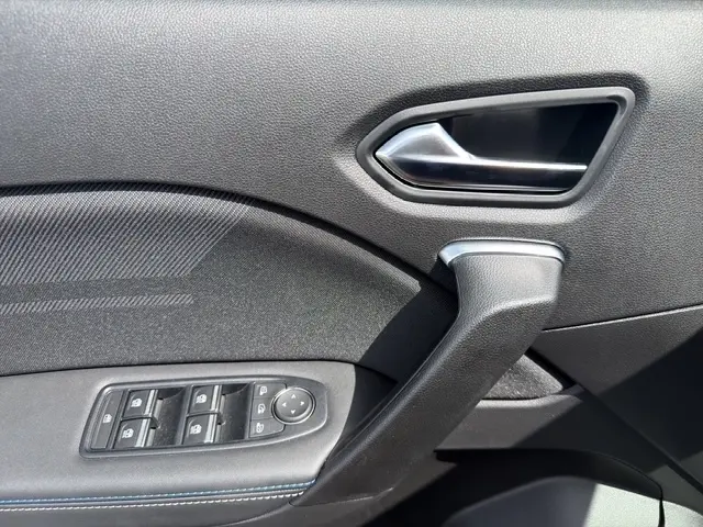 Détail de la porte intérieure côté conducteur du Renault Captur blanc, avec poignée argentée et commandes des vitres.
