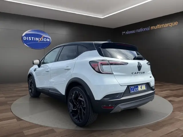 Vue 3/4 arrière droite du Renault Captur blanc bi-ton esprit Alpine avec jantes noires dans un showroom.