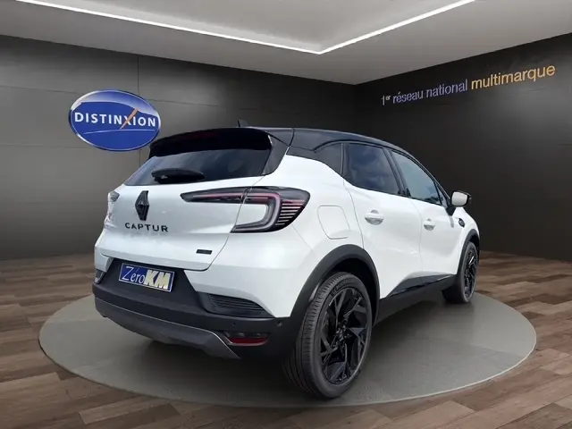 Vue 3/4 arrière droite du Renault Captur blanc bi-ton avec toit noir et jantes noires dans un showroom.