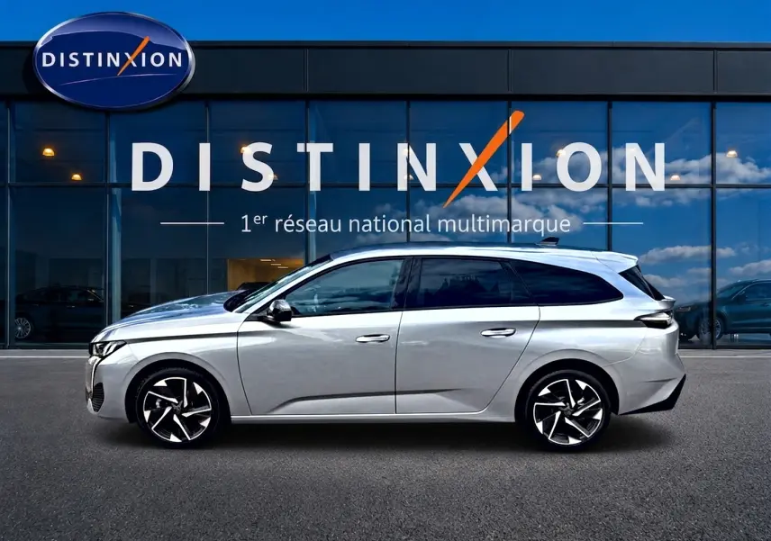 Peugeot 308 SW gris vue de profil côté gauche, avec jantes alliage et vitres surteintées, devant un showroom Distinxion.