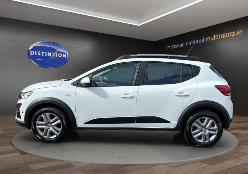 Vue latérale droite d'une Dacia Sandero Stepway blanche avec protections noires et jantes alliage en showroom.