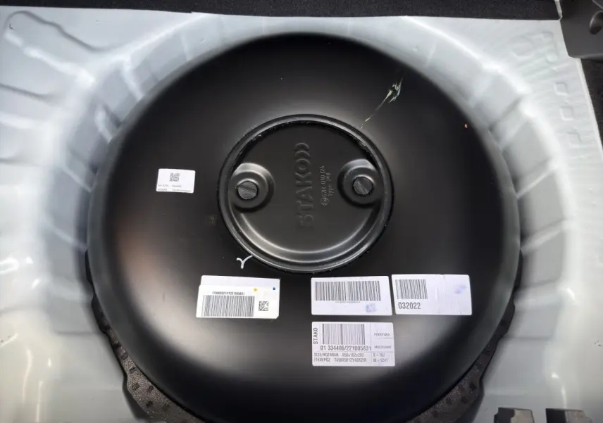 Réservoir GPL noir circulaire vu de dessus dans le coffre d'une Dacia Sandero Stepway blanche.