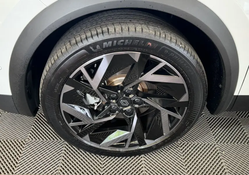 Gros plan sur la roue avant droite du Renault Captur blanc 2025 avec jante alliage noir et gris au design géométrique.