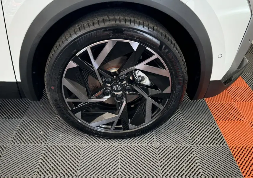 Gros plan sur la roue avant droite du Renault Captur blanc esprit Alpine E-Tech, jante noire et argent au design géométrique.