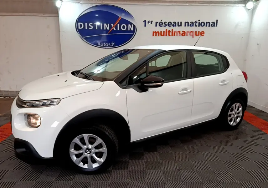 Citroën C3 blanche vue de profil côté gauche dans un showroom avec logo Distinxion en arrière-plan.